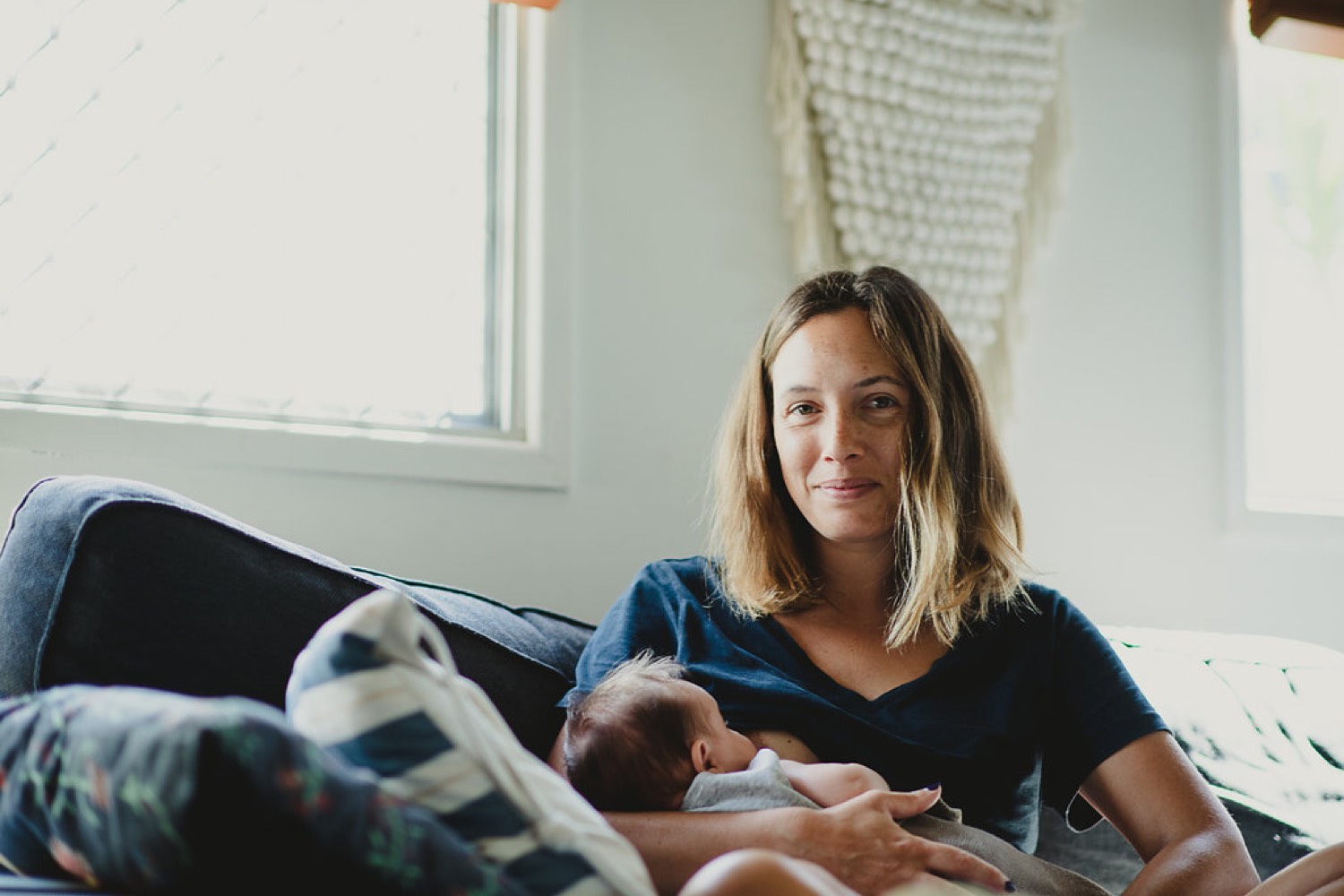 Mother breastfeeding her newborn on the couch