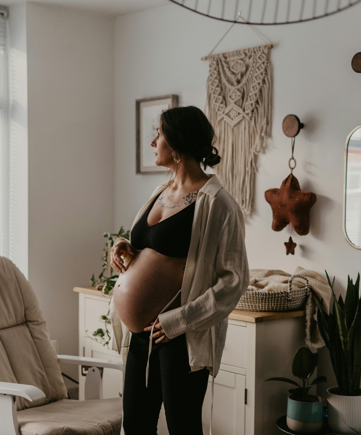 Expectant mother cradling her belly in the nursery